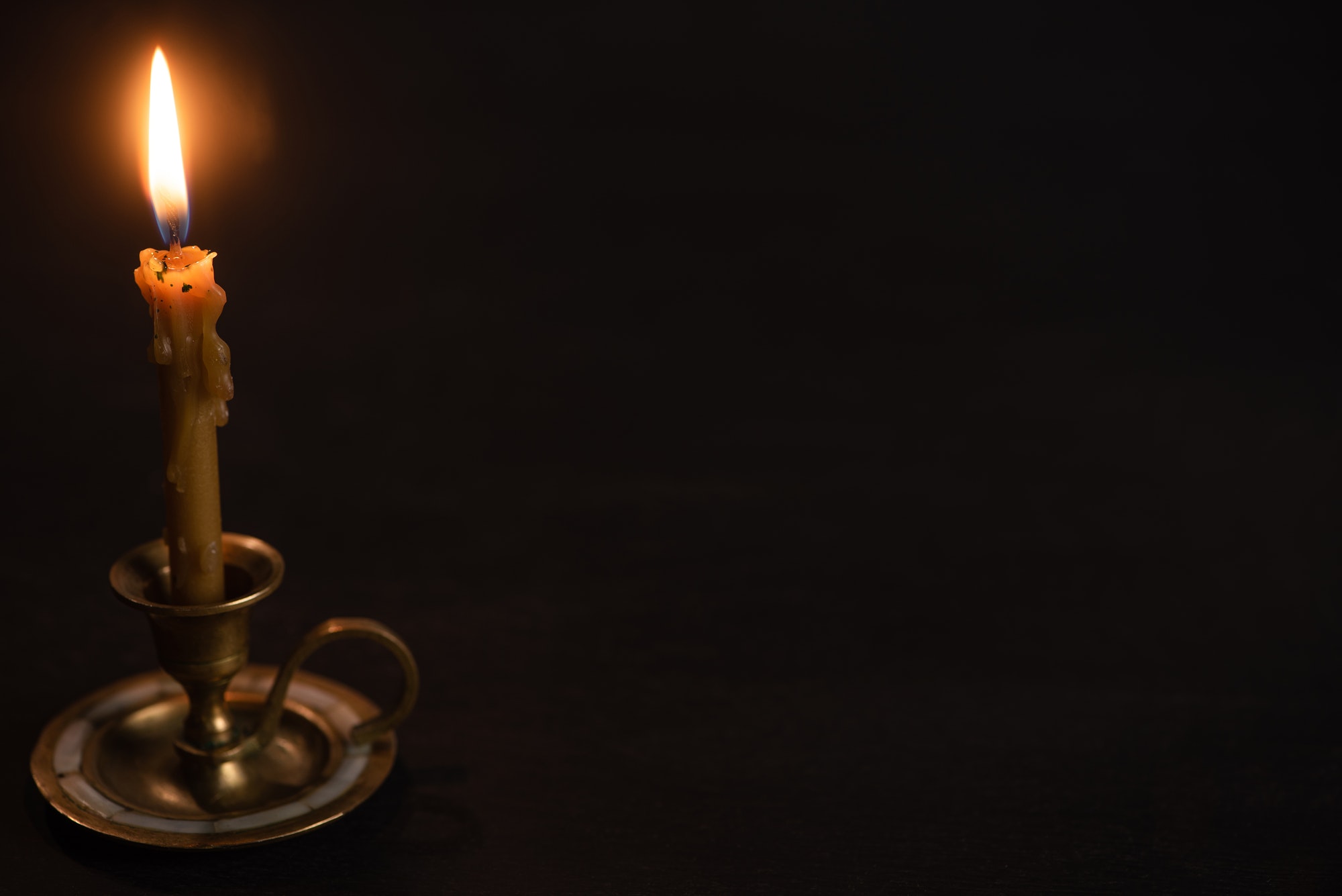 Church Candle in Candlestick Burning in Dark