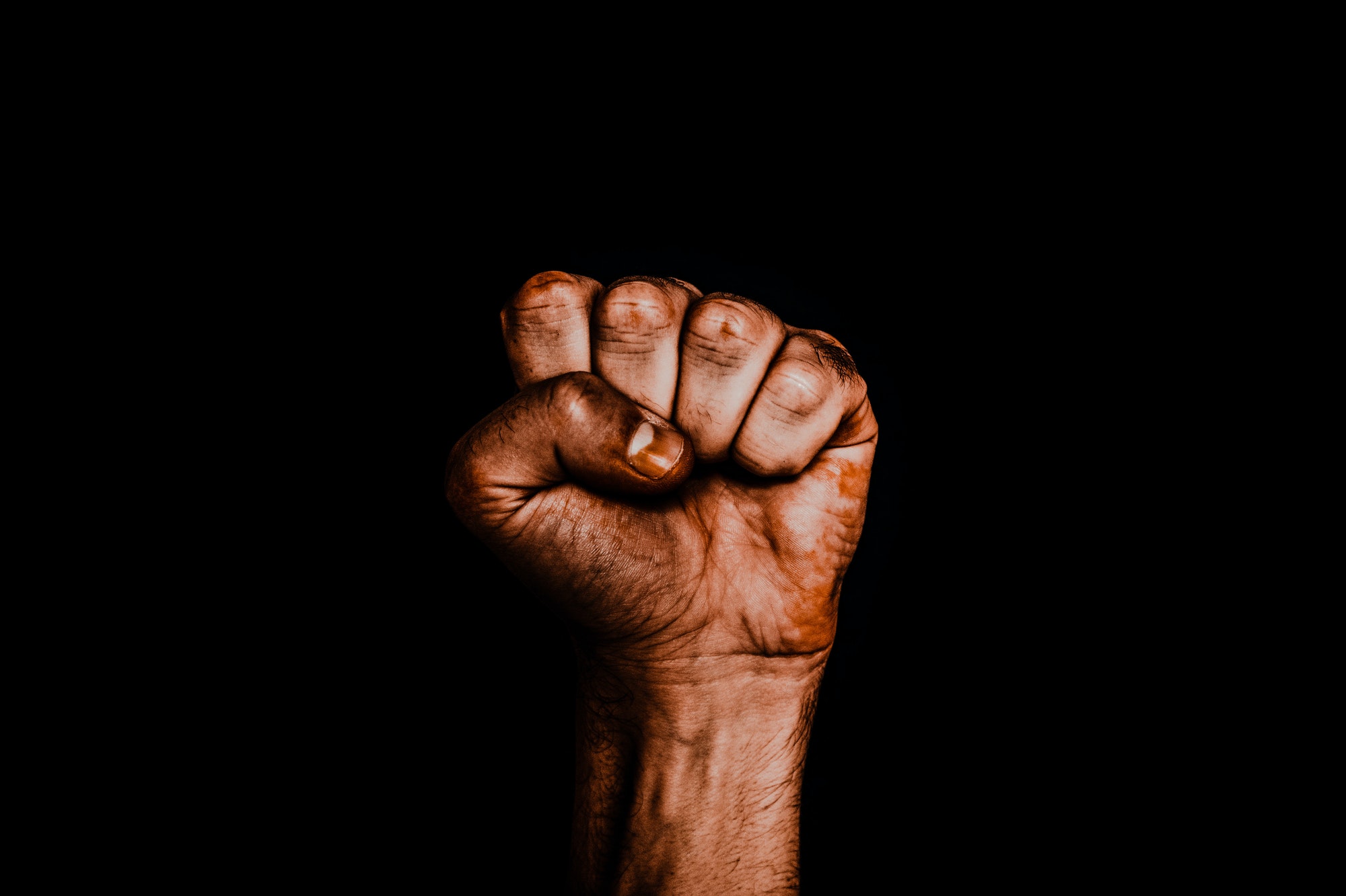Male hand clenched into a fist. The black life of matter.