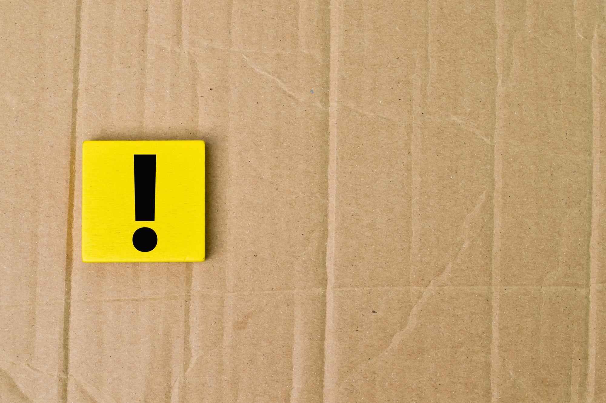 Exclamation mark drawn on wooden board over cork background with copy space.