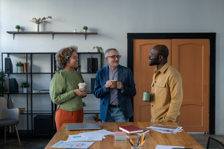 Three confident intercultural colleagues having talk at break